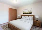 Thumbnail 5 of 6 - A bedroom with a large bed, a wooden headboard, and a painting above the bed. Bismarck, ND Parkview Arms Apartments