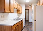 Thumbnail 7 of 17 - A kitchen with wooden cabinets and a white sink. Fargo, ND Southgate Apartments