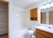 Thumbnail 21 of 23 - A white bathroom with a toilet, sink, and a large mirror. Fargo, ND Summit Point