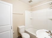 Thumbnail 6 of 7 - A white toilet sits next to a white sink in a small bathroom. Fargo, ND Birchwood Apartments