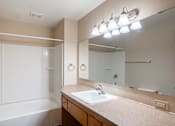 Thumbnail 10 of 12 - A bathroom with a sink, mirror, and tub. Fargo, ND L&R Apartments