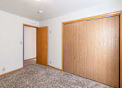 Thumbnail 9 of 12 - A room with a brown door and a brown wardrobe. Fargo, ND L&R Apartments