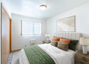 Thumbnail 4 of 12 - A bedroom with a bed, two lamps, and a mirror. Fargo, ND L&R Apartments