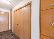 Thumbnail 11 of 12 - A hallway with three wooden doors. Fargo, ND L&R Apartments