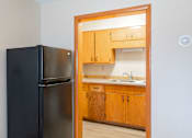 Thumbnail 4 of 7 - A black refrigerator is in a kitchen with wooden cabinets. Fargo, ND Birchwood Apartments