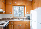 Thumbnail 5 of 12 - A kitchen with wooden cabinets and a white refrigerator. Fargo, ND L&R Apartments