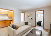 Thumbnail 1 of 7 - A living room with a couch, a coffee table, and a television. Fargo, ND Birchwood Apartments