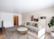 Thumbnail 2 of 12 - A living room with a white couch, a coffee table, and a television. Fargo, ND L&R Apartments