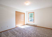 Thumbnail 38 of 54 - A bedroom with a carpeted floor, a door, a window. Fargo, ND Stonebridge Apartments