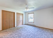 Thumbnail 42 of 54 - A room with a carpeted floor, a ceiling fan, and a window with blinds. Fargo, ND Stonebridge Apartments