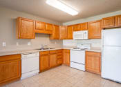 Thumbnail 19 of 54 - A kitchen with wooden cabinets and white appliances. Fargo, ND Stonebridge Apartments