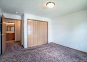 Thumbnail 14 of 54 - A room with a carpeted floor and a wooden door. Fargo, ND Stonebridge Apartments
