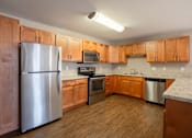 Thumbnail 15 of 48 - A kitchen with wooden cabinets and a stainless steel refrigerator. Fargo, ND Urban Plains Apartments