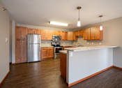 Thumbnail 14 of 48 - A kitchen with wooden cabinets and a white counter. Fargo, ND Urban Plains Apartments