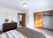 Thumbnail 10 of 10 - A bedroom with a bed, nightstand, and a painting on the wall. Fargo, ND Carr Apartments