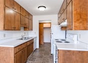 Thumbnail 6 of 10 - A kitchen with brown cabinets and white appliances. Fargo, ND Carr Apartments