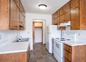 Thumbnail 5 of 10 - A kitchen with wooden cabinets and a white stove top oven. Fargo, ND Carr Apartments