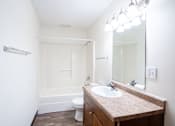 Thumbnail 20 of 42 - A bathroom with a toilet, sink, mirror, and light fixture. Fargo, ND Westwood Estates