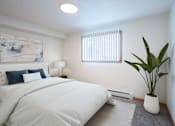 Thumbnail 2 of 46 - A bedroom with a large bed, a potted plant, and a painting on the wall. Grand Forks, ND Cherry Creek Apartments