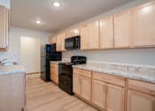 Thumbnail 39 of 46 - A kitchen with wooden cabinets and black appliances. Cherry Creek Apartments