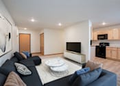 Thumbnail 1 of 46 - A modern living room with a black couch and a white coffee table. Grand Forks, ND Cherry Creek Apartments
