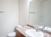 Thumbnail 20 of 20 - A bathroom with a toilet, sink and mirror. Fargo, ND Kennedy Apartments