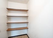 Thumbnail 21 of 23 - A white wall with three shelves and a black and white floor.