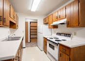 Thumbnail 16 of 23 - A kitchen with white appliances and wooden cabinets.
