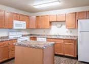 Thumbnail 14 of 20 - A kitchen with wooden cabinets and a granite countertop. Fargo, ND Kennedy Apartments