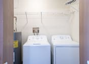 Thumbnail 18 of 20 - Two white front loading washing machines in a small laundry room. Fargo, ND Kennedy Apartments