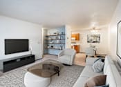 Thumbnail 1 of 23 - A living room with a grey sofa, a glass coffee table, and a television. Fargo, ND Countryside Apartments