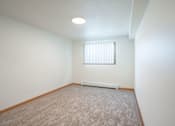 Thumbnail 33 of 46 - A room with a carpeted floor and a window with blinds. Cherry Creek Apartments