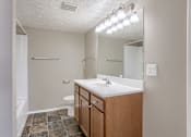 Thumbnail 33 of 34 - A bathroom with a sink, toilet, and mirror. Omaha, NE Evergreen Terrace Apartments