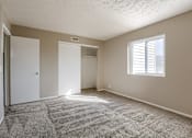 Thumbnail 30 of 34 - A room with a carpeted floor and a window with blinds. Omaha, NE Evergreen Terrace Apartments