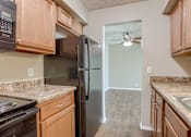 Thumbnail 26 of 34 - A kitchen with a black refrigerator and wooden cabinets. Omaha, NE Evergreen Terrace Apartments