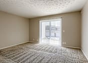 Thumbnail 22 of 34 - A room with a carpeted floor and a sliding glass door. Omaha, NE Evergreen Terrace Apartments