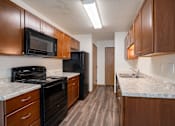 Thumbnail 14 of 39 - A kitchen with dark wood cabinets and black appliances. Grand Forks, ND Columbia West Apartments