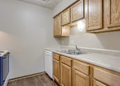 Thumbnail 19 of 29 - A kitchen with wooden cabinets and a white dishwasher. Omaha, NE Stony Brook Apartments