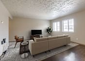 Thumbnail 2 of 29 - A living room with a couch, chair, and television. Omaha, NE Stony Brook Apartments
