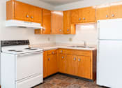 Thumbnail 12 of 20 - A kitchen with wooden cabinets and a white refrigerator. Fargo, ND Morningside Apartments