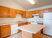 Thumbnail 11 of 43 - A kitchen with wooden cabinets and white appliances. Bismarck, ND Sierra Ridge Apartments