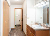 Thumbnail 26 of 30 - A bathroom with a sink, mirror, and wooden cabinets. Fargo, ND Long Island Apartments