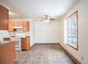 Thumbnail 20 of 30 - A kitchen with brown cabinets and a tiled floor. Fargo, ND Long Island Apartments