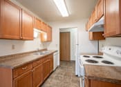 Thumbnail 19 of 30 - A kitchen with brown cabinets and a white stove. Fargo, ND Long Island Apartments