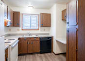 Thumbnail 15 of 23 - A kitchen with wooden cabinets and a black dishwasher. West Fargo, ND Parkwest Gardens