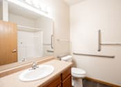 Thumbnail 18 of 24 - A bathroom with a toilet, sink, and mirror. Fargo, ND North Sky II Apartments