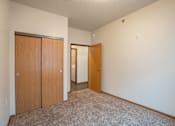 Thumbnail 14 of 24 - A room with a carpeted floor and two wooden doors. Fargo, ND North Sky II Apartments