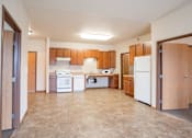 Thumbnail 3 of 24 - A kitchen with brown cabinets and a white refrigerator. Fargo, ND North Sky II Apartments