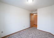 Thumbnail 17 of 25 - A room with a carpeted floor and a wooden door. Fargo, ND Park Place Apartments