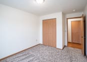 Thumbnail 18 of 25 - A room with a carpeted floor and two wooden doors. Fargo, ND Park Place Apartments